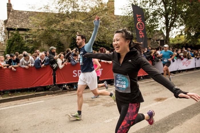 Katie Myint running with her arms out stretched at the end a race, looking very pleased