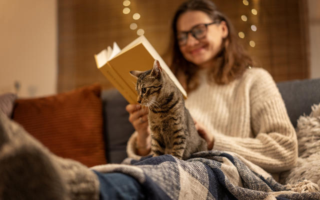 Woman reading, cat on lap