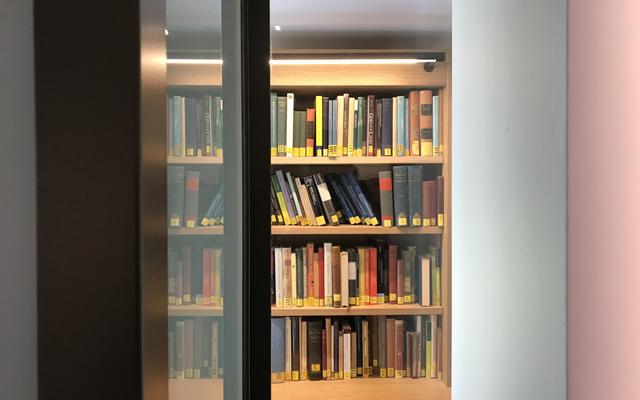 A view from an open glass door of books on a shelf