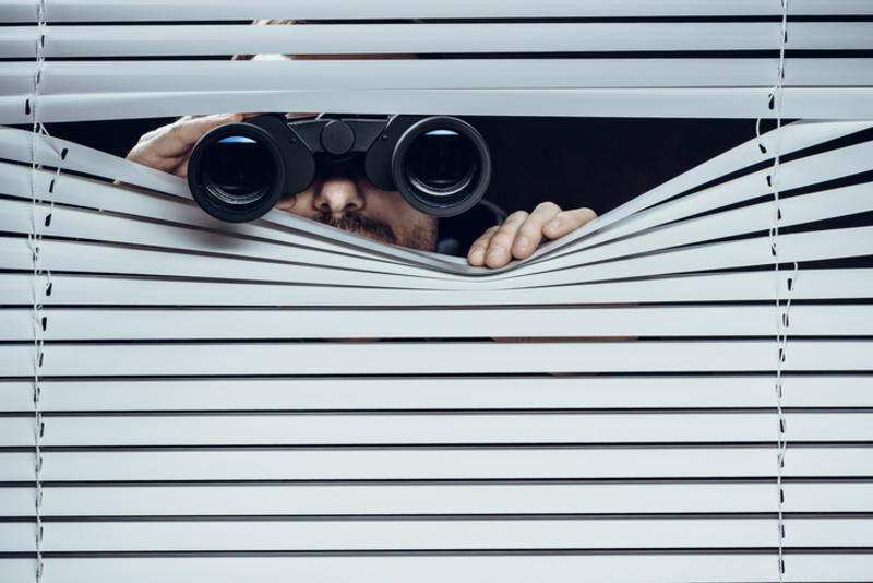 Man looking through a blind with binoculars