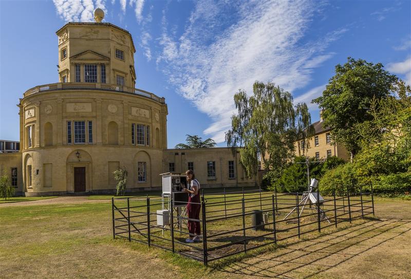 A student using scientific equipment to record the temperature in front of the Radcliffe Observatory in Oxford