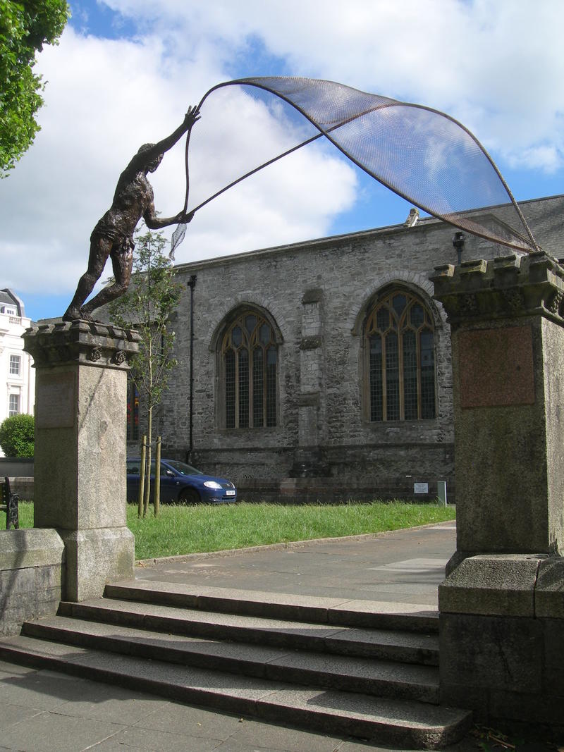A sculpture of St. Andrew casting his net across two 3m. high pillars in front of the Minster Church in Plymouth.