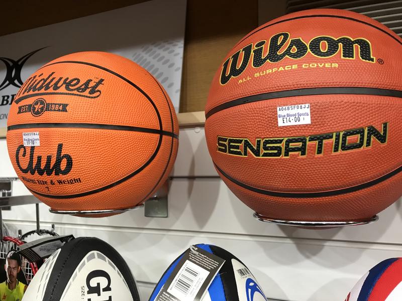 Two basketballs on a shelf in a sports shop, with the price stickers with the shop name 'Blue Blood'