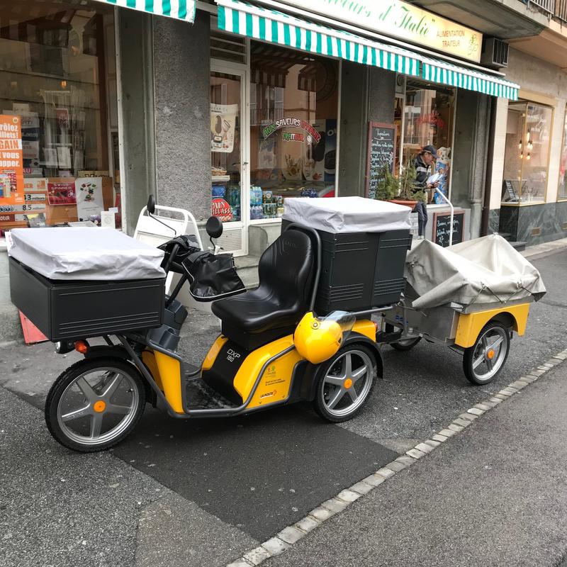 A Swiss Post electric vehicle parked outside a shop
