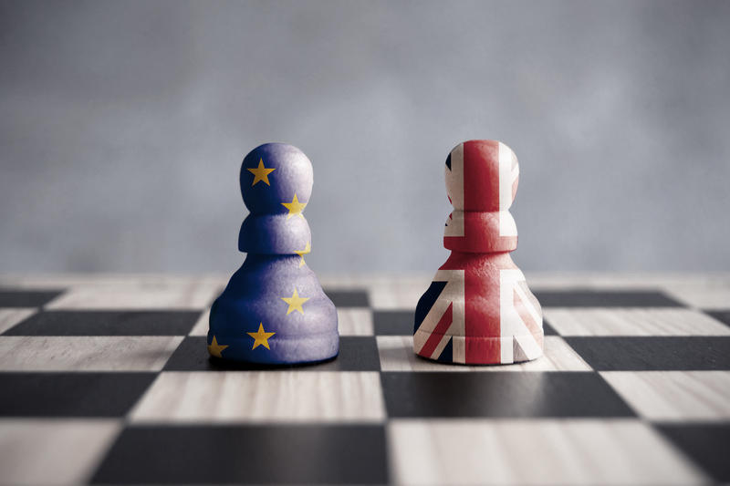 Two chess pieces on a board - one is painted in the colours of the EU flag, the other in the colours of the British flag