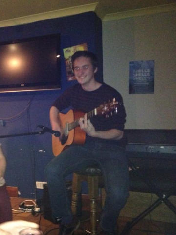 Rory Irwin playing the guitar at an open mic night at St. Anne's